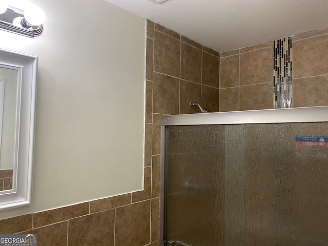 bathroom featuring a shower with door and tile walls