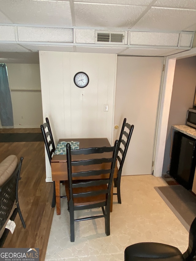 dining area featuring a drop ceiling and light hardwood / wood-style floors