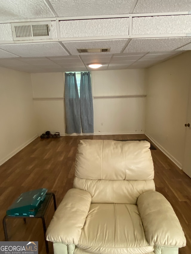 living room featuring a drop ceiling and dark wood-type flooring