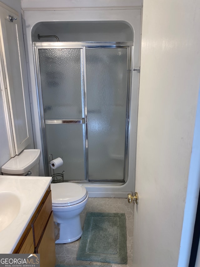 bathroom featuring tile patterned flooring, an enclosed shower, vanity, and toilet