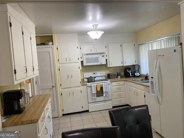 kitchen featuring white cabinets, sink, light tile patterned floors, and white appliances