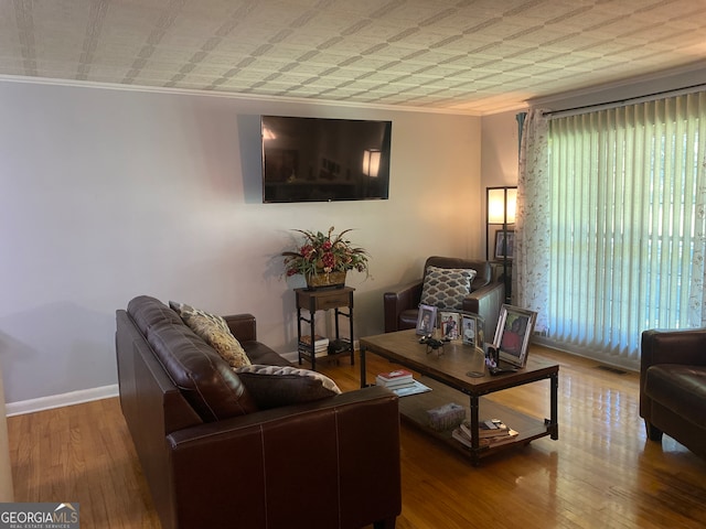 living room with crown molding, a wealth of natural light, and hardwood / wood-style floors