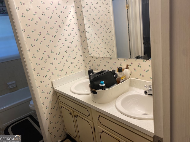 bathroom featuring vanity, a tub to relax in, and toilet