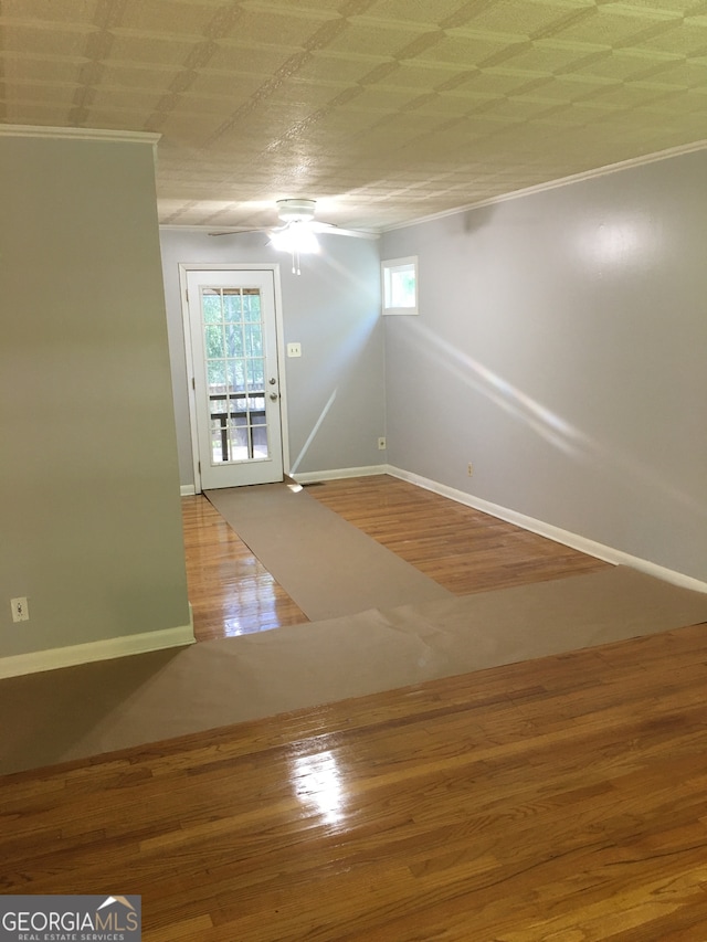 spare room featuring wood-type flooring, crown molding, and ceiling fan