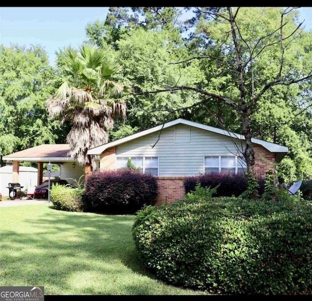 view of side of home with a yard, an attached carport, and brick siding