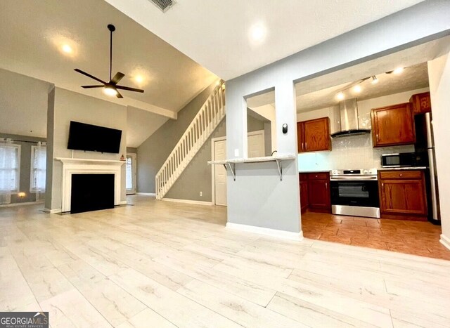 unfurnished living room with sink, a towering ceiling, ceiling fan, and light wood-type flooring