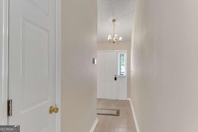 foyer entrance with a textured ceiling, light hardwood / wood-style flooring, and a chandelier