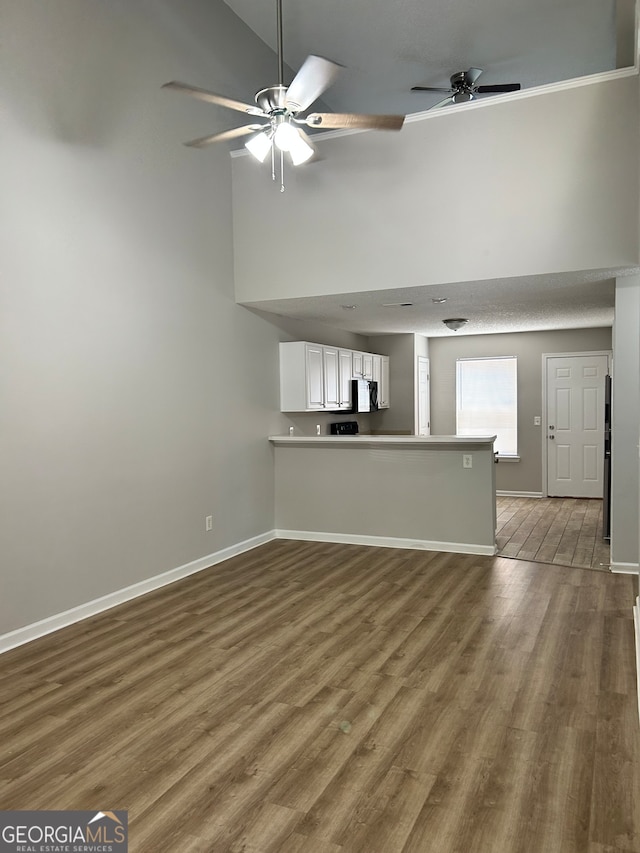 unfurnished living room featuring high vaulted ceiling, ceiling fan, and wood-type flooring