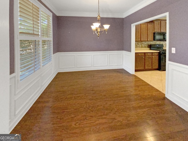 unfurnished dining area with ornamental molding, light wood-style floors, and an inviting chandelier