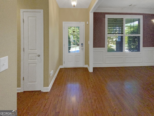 foyer with a wainscoted wall, ornamental molding, and wood finished floors