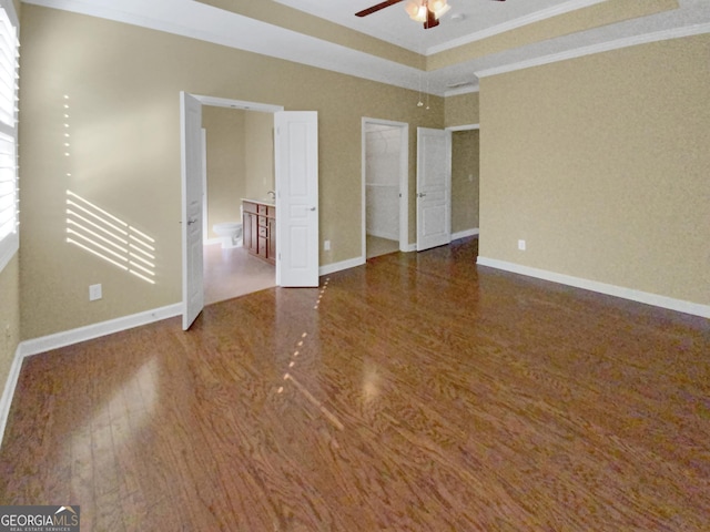 unfurnished bedroom with crown molding, baseboards, dark wood-style flooring, and ensuite bathroom