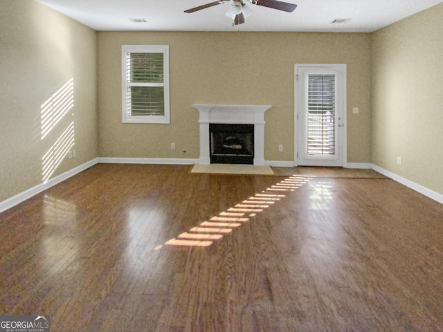 unfurnished living room featuring baseboards, a fireplace with flush hearth, visible vents, and dark wood-style flooring