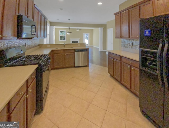 kitchen featuring decorative light fixtures, light countertops, brown cabinetry, a sink, and black appliances