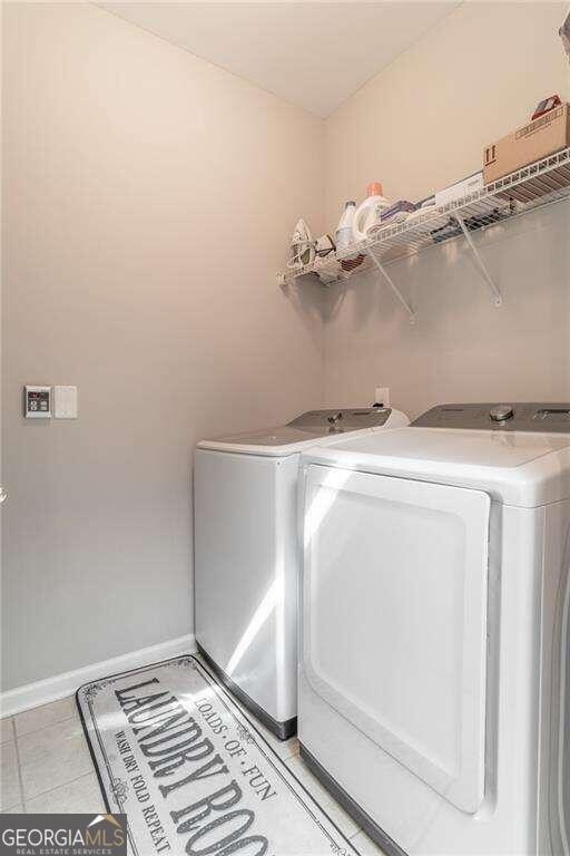 laundry room with light tile patterned floors and washer and clothes dryer