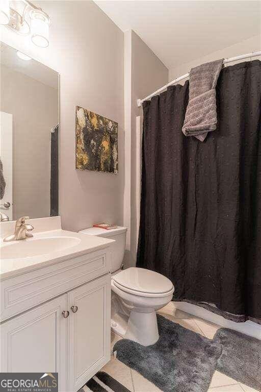 bathroom with tile patterned floors, toilet, vanity, and a shower with curtain