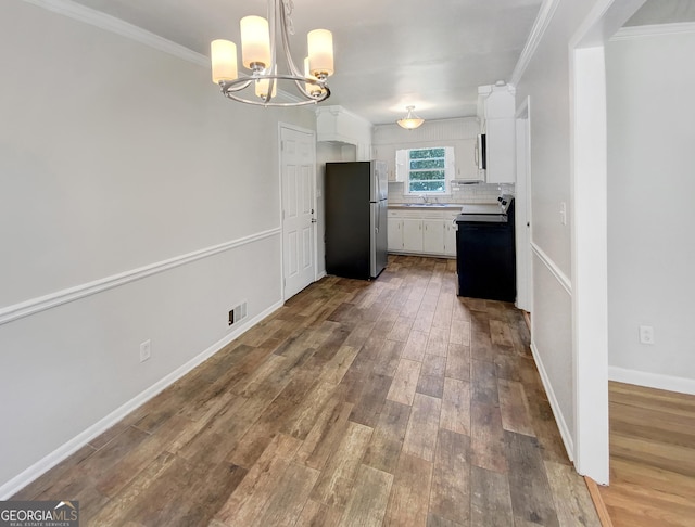 kitchen with white cabinets, black range with electric stovetop, freestanding refrigerator, light countertops, and a sink