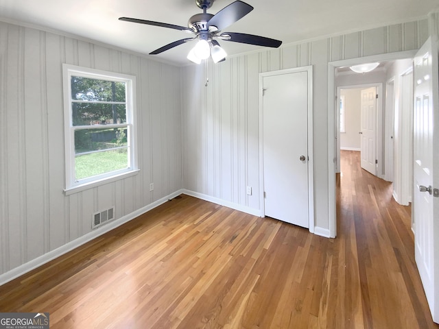 empty room featuring wood finished floors, visible vents, and baseboards