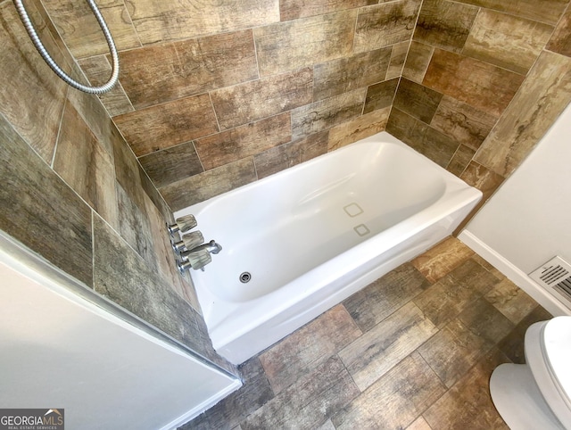 bathroom with visible vents, bathing tub / shower combination, toilet, and baseboards