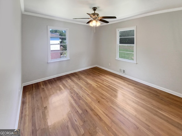 spare room featuring baseboards, visible vents, crown molding, and wood finished floors