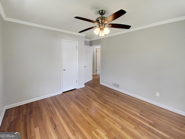 unfurnished bedroom featuring crown molding, light wood finished floors, visible vents, and baseboards