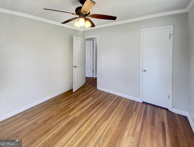 unfurnished bedroom with ceiling fan, crown molding, baseboards, and wood finished floors