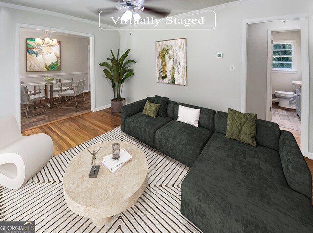 living room with ceiling fan with notable chandelier, crown molding, and light hardwood / wood-style floors