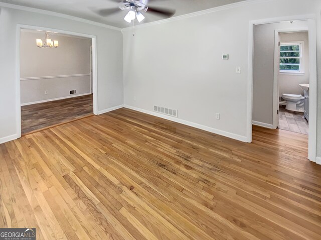 empty room featuring ceiling fan with notable chandelier, ornamental molding, and light wood-type flooring