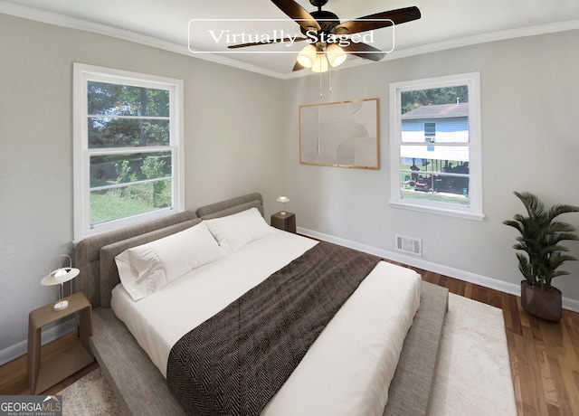 bedroom featuring wood finished floors, a ceiling fan, baseboards, visible vents, and crown molding