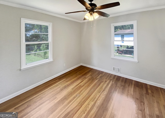 unfurnished room featuring crown molding, light wood-style flooring, visible vents, and baseboards