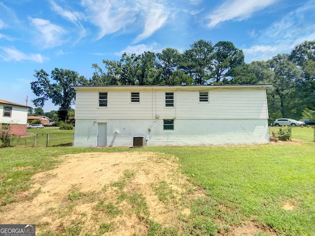 rear view of property featuring a yard, cooling unit, and fence