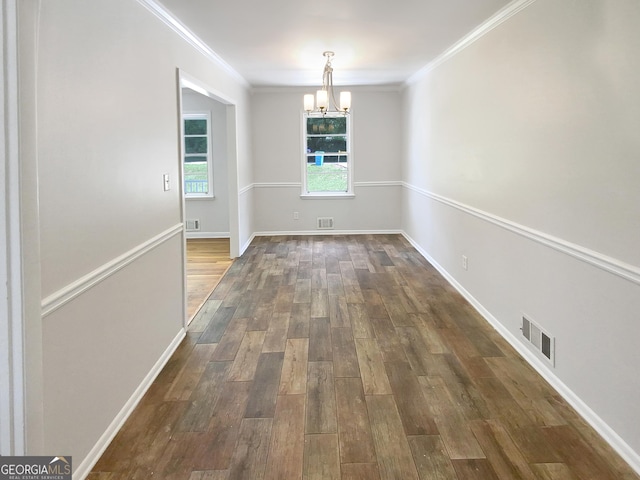 unfurnished dining area featuring dark wood-style floors, crown molding, visible vents, a chandelier, and baseboards