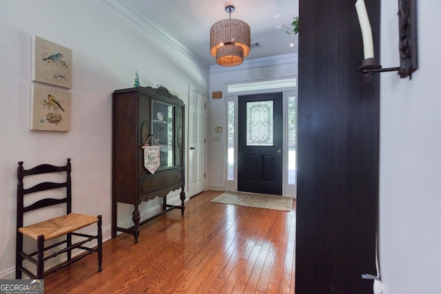 foyer entrance with crown molding, an inviting chandelier, and wood-type flooring