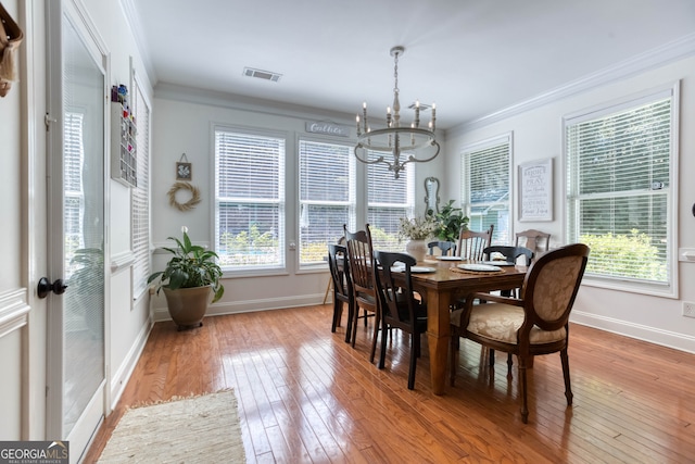 dining area with plenty of natural light, a notable chandelier, and hardwood / wood-style flooring