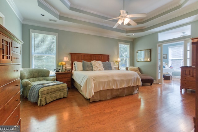 bedroom with a tray ceiling, wood-type flooring, ornamental molding, and ceiling fan