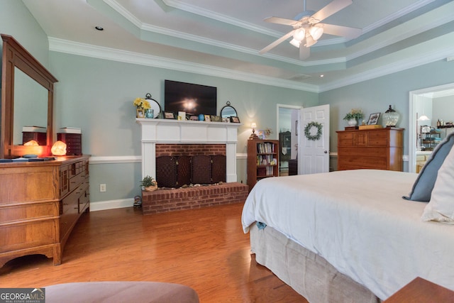 bedroom featuring ornamental molding, wood-type flooring, a tray ceiling, and ceiling fan