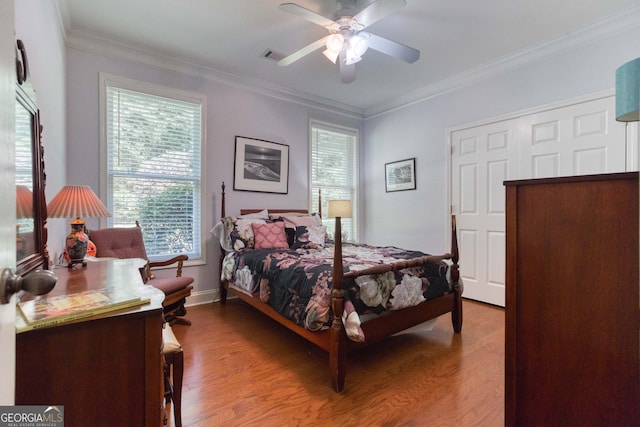 bedroom featuring multiple windows, wood-type flooring, ornamental molding, and ceiling fan