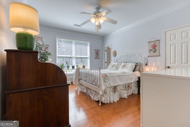 bedroom with wood-type flooring, crown molding, and ceiling fan