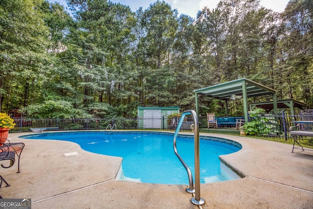 view of swimming pool featuring a diving board, a storage shed, and a patio