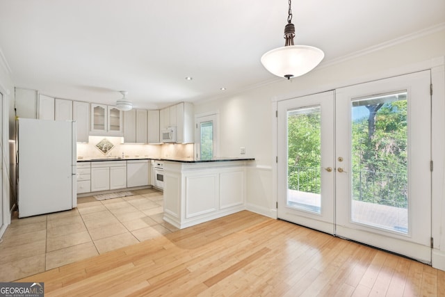 kitchen featuring french doors, light wood finished floors, ornamental molding, white appliances, and a peninsula