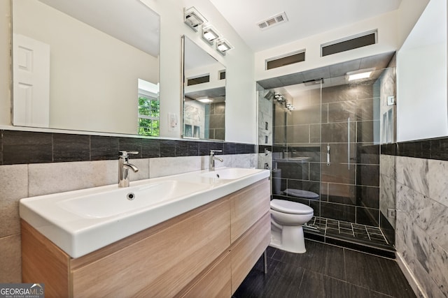 bathroom featuring toilet, a shower with door, vanity, backsplash, and tile walls