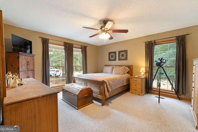 carpeted bedroom featuring ceiling fan and a textured ceiling