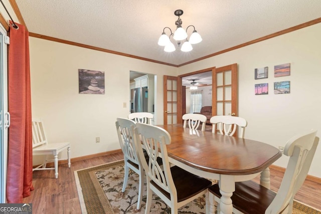 dining space with french doors, dark wood-type flooring, crown molding, a textured ceiling, and ceiling fan with notable chandelier