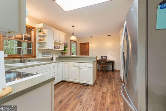 kitchen with white cabinetry, hanging light fixtures, kitchen peninsula, and stainless steel fridge