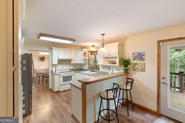 kitchen featuring sink, kitchen peninsula, hanging light fixtures, white cabinets, and white electric range