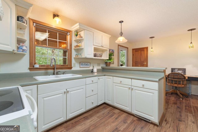 kitchen featuring dark hardwood / wood-style floors, kitchen peninsula, white range oven, decorative light fixtures, and white cabinetry