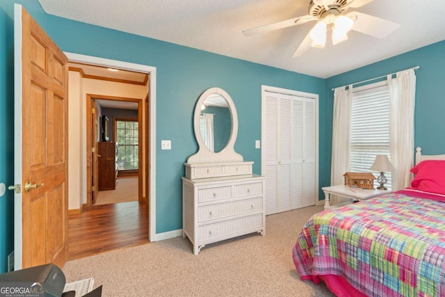 bedroom featuring light carpet, a textured ceiling, a closet, and ceiling fan