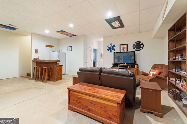 living room featuring a drop ceiling and bar