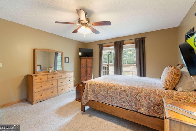 carpeted bedroom featuring ceiling fan and a textured ceiling