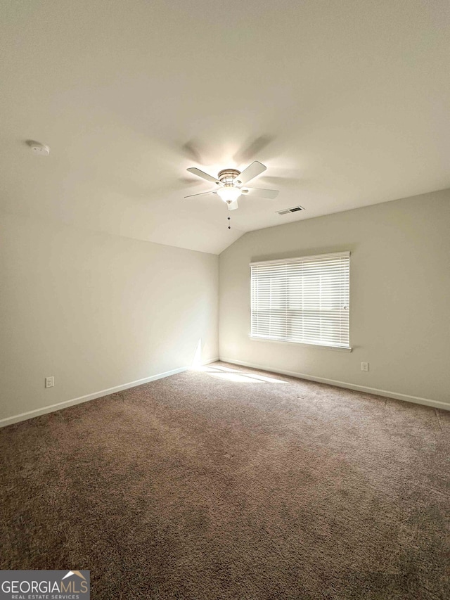 empty room featuring carpet, vaulted ceiling, and ceiling fan