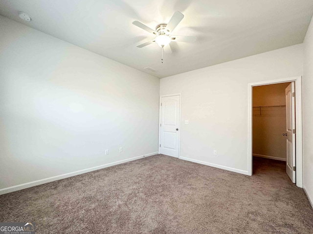 unfurnished bedroom with carpet flooring, a walk in closet, ceiling fan, and a closet